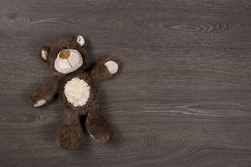 Image showing Brown teddy bear on wooden background, top view