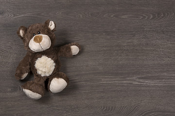 Image showing Brown teddy bear on wooden background, top view