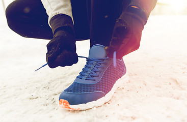 Image showing close up of man tying shoe lace in winter outdoors