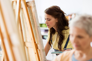 Image showing student girl with easel painting at art school