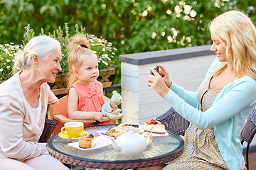 Image showing woman photographing her family at cafe