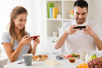 Image showing couple with smartphones having breakfast at home