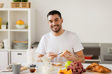 Image showing man eating toast with coffee at home kitchen