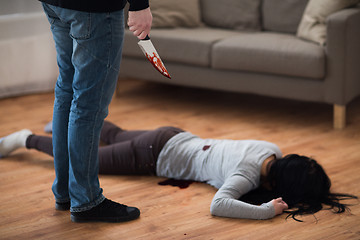 Image showing criminal with knife and dead body at crime scene