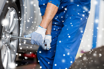 Image showing auto mechanic with screwdriver changing car tire