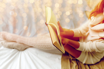 Image showing close up of young woman reading book in bed