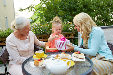 Image showing happy mother giving present to little daughter at cafe