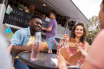 Image showing happy friends with drinks eating at food truck