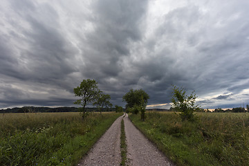 Image showing Dirt road and the dark cloudy sky