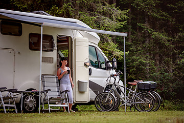 Image showing Woman is standing with a mug of coffee near the camper RV.