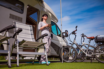 Image showing Woman is standing with a mug of coffee near the camper RV.