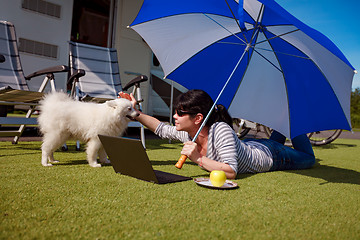 Image showing Woman on the grass with a dog looking at a laptop