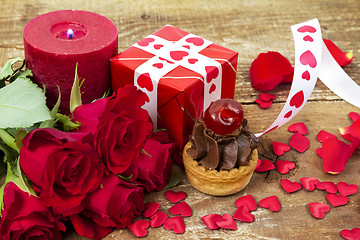 Image showing Cupcake with cherry in front of bouquet of red roses