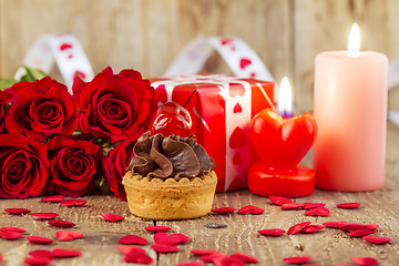 Image showing Cupcake with cherry in front of bouquet of red roses and cadles