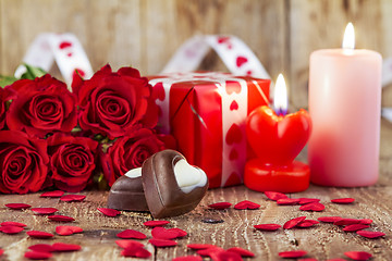 Image showing Chocolate pralines in front of bouquet of red roses