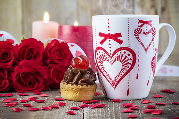 Image showing Cupcake with cherry in front of bouquet of red roses