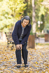 Image showing Senior woman having knee pain walking in park