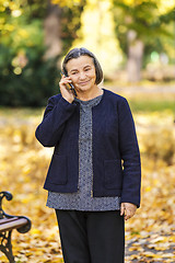 Image showing Senior woman talking on smartphone outdoors