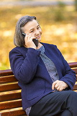 Image showing Senior woman talking on smartphone outdoors
