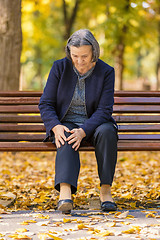 Image showing Senior woman having knee pain walking in park