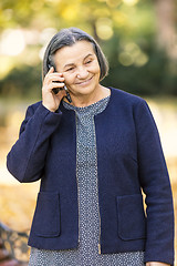 Image showing Positive senior woman talking on smartphone outdoors