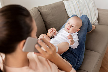 Image showing mother with baby calling on smartphone at home