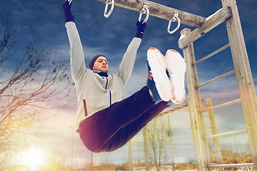 Image showing young man exercising on horizontal bar in winter