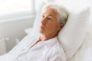 Image showing sad senior woman lying on bed at hospital ward