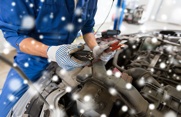 Image showing auto mechanic hands with cleats charging battery