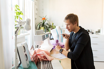 Image showing fashion designer with smartphone working at studio