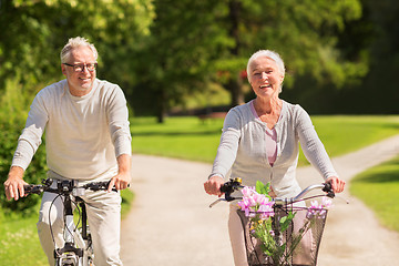 Image showing happy senior couple riding bicycles at summer park