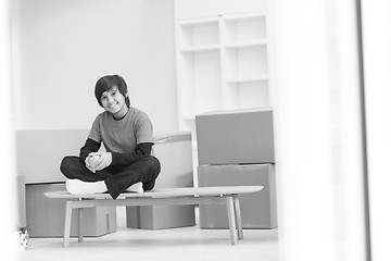 Image showing boy sitting on the table with cardboard boxes around him