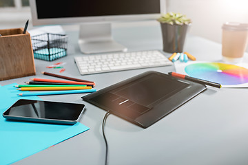 Image showing The gray desk with laptop, notepad with blank sheet, pot of flower, stylus and tablet for retouching