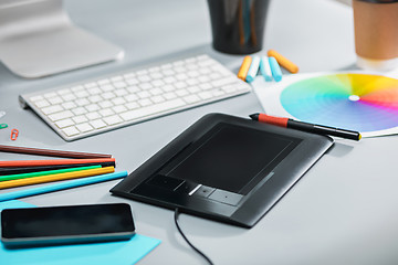 Image showing The gray desk with laptop, notepad with blank sheet, pot of flower, stylus and tablet for retouching