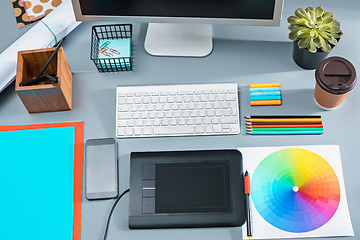 Image showing The gray desk with laptop, notepad with blank sheet, pot of flower, stylus and tablet for retouching