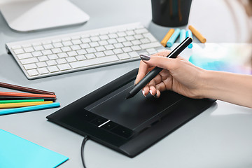 Image showing The gray desk with laptop, notepad with blank sheet, pot of flower, stylus and tablet for retouching