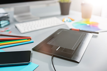 Image showing The gray desk with laptop, notepad with blank sheet, pot of flower, stylus and tablet for retouching