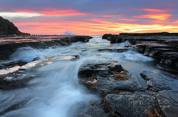 Image showing Sunrise waves flowing into rock chasm seascape