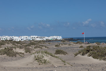 Image showing The red flag weighs in the wind at Surfers Beach Famara on Lanza