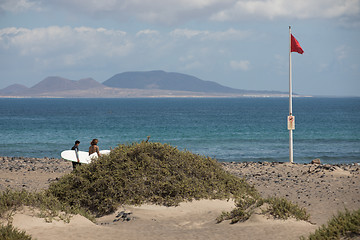 Image showing The red flag weighs in the wind at Surfers Beach Famara on Lanza