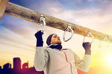 Image showing young man exercising on horizontal bar in winter