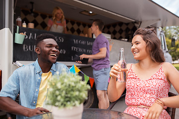 Image showing friends with drinks sitting at table at food truck