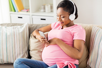 Image showing pregnant woman in headphones with smartphone