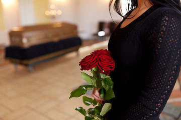 Image showing close up of woman with roses and coffin at funeral