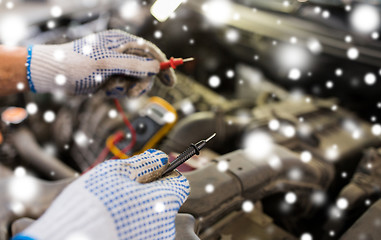 Image showing auto mechanic hands with multimeter at car