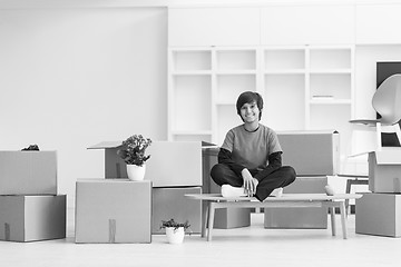 Image showing boy sitting on the table with cardboard boxes around him