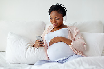 Image showing pregnant woman in headphones with smartphone