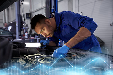 Image showing mechanic man with lamp repairing car at workshop