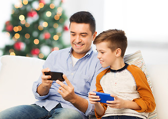 Image showing happy father and son with smartphones at christmas