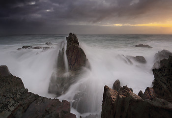 Image showing Stormy sunrise and waves crash over sea stacks